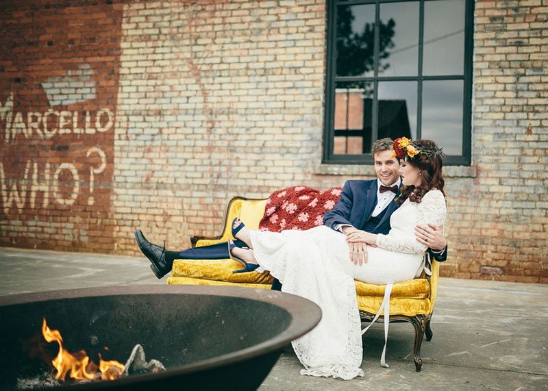 Industrial_Warehouse_Shoot-bride_and_groom_sitting_on_couch_by_fire