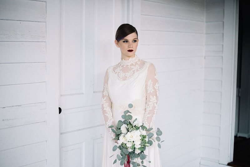 Vintage_Winter_Bridal-bride_holding_flowers_outside_white_house