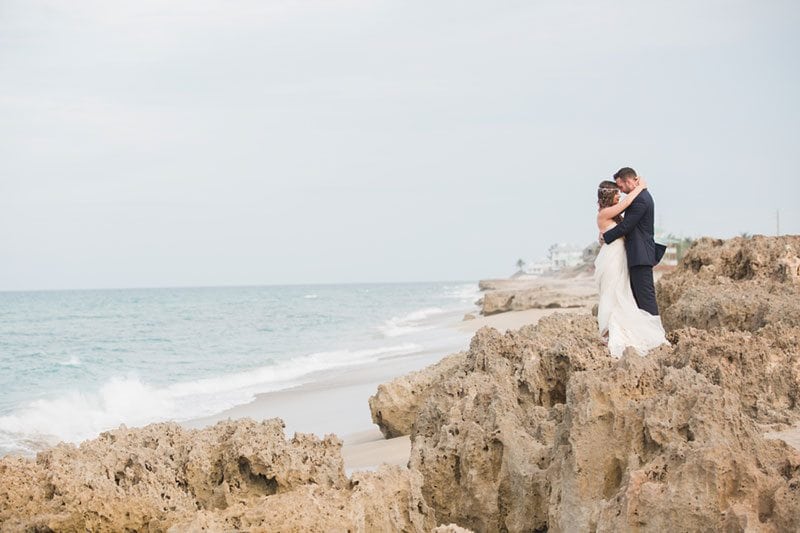 Chic_Coastal_Wedding-bride_and_groom_standing_on_rocky_beach