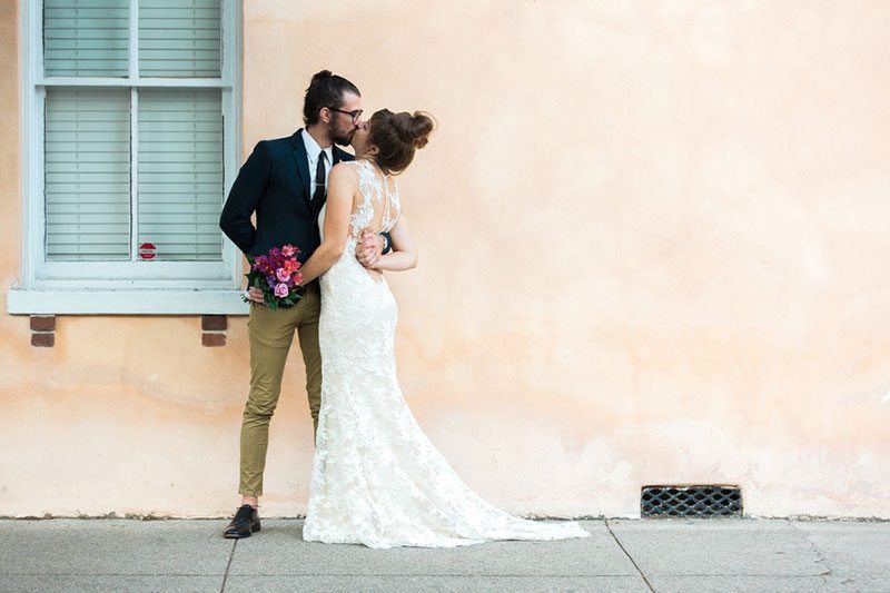 French_Boho-bride_and_groom_kissing_peach_backdrop