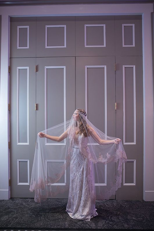 Kate_McDonald-bride_holding_veil_against_doors
