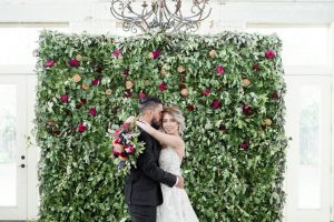 Vintage Copper Bride And Groom Hugging In Front Of Flower Wall
