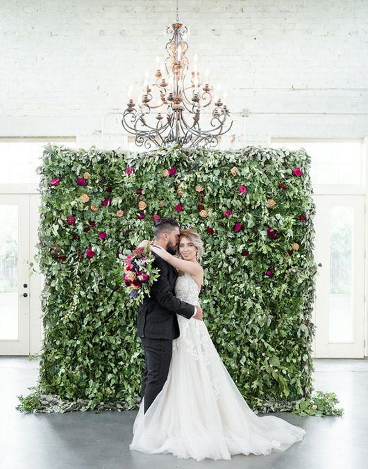 Vintage Copper Bride And Groom Hugging In Front Of Flower Wall