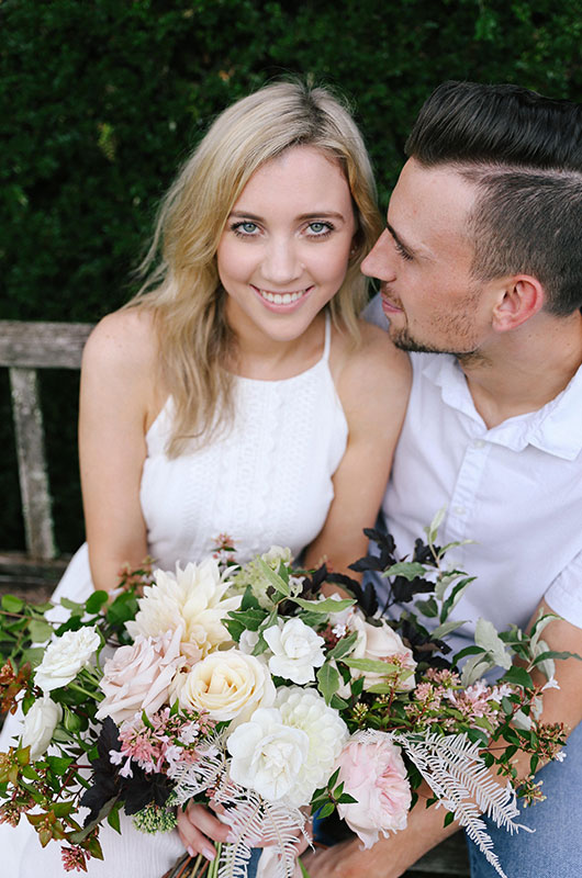 Emily And Justin Sitting On Bench With Flowers