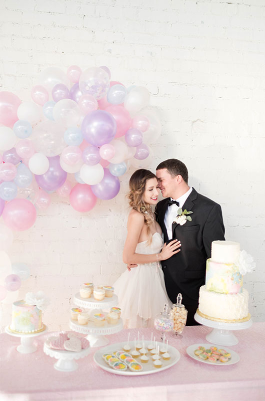 Pastel And Watercolor Styled Shoot Bride And Groom Behind Dessert Table