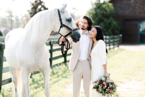 The Heart Races Styled Shoot A Playful Take On Equestrian Bridal Bride And Groom Looking Over At Horse In Stable
