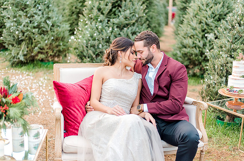 Dreamy Christmas Tree Styled Shoot Bride And Groom Sitting On Sofa And Touching Noses
