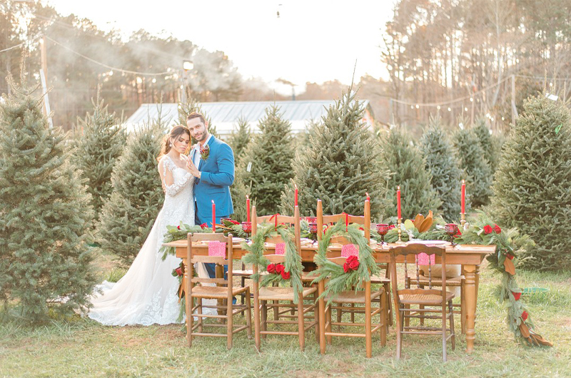 Dreamy Christmas Tree Styled Shoot Bride In Lace Dress And Groom Standing Next To Festive Table