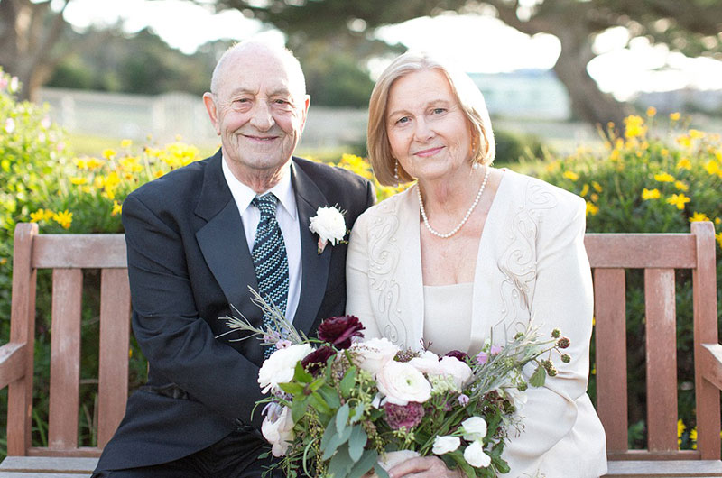 A Valentine’s Oceanfront Vow Renewal To Celebrate 55 Years Couple On Bench Looking At Camera