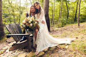 Spring 2020 Cover Couple Singer Rachel Reinert & Musician Caleb Crosby Hit A Perfect Note With Their Boho Chic Wedding Style Couple Sitting On Adirondak Chair (1)
