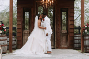 A Rustic And Elegant Barn Wedding In Bayou Country Couple Kissing With Chandelier And Wine Barrels