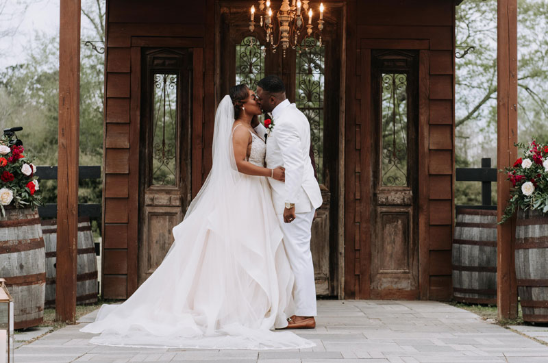 A Rustic And Elegant Barn Wedding In Bayou Country Couple Kissing With Chandelier And Wine Barrels A Rustic And Elegant Barn Wedding In Bayou Country Couple Kissing With Chandelier And Wine Barrels