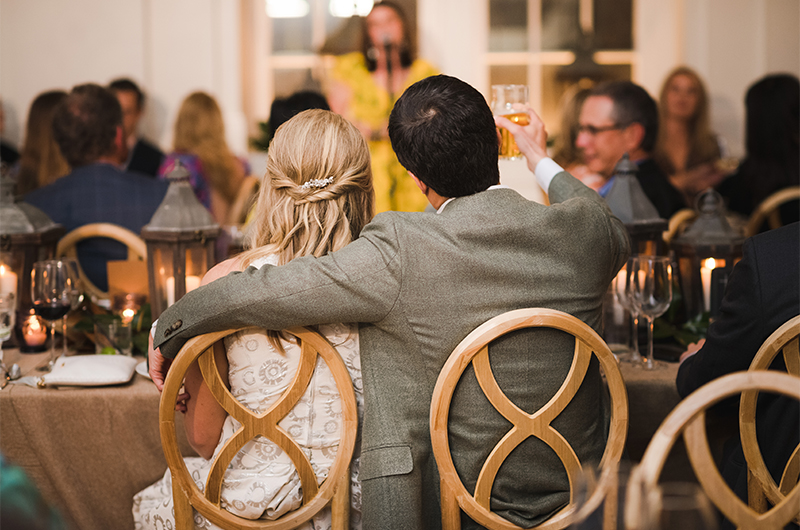 Tips To Guarantee Your Rehearsal Dinner Is A Memorable Affair Couple Enjoys Toast Together Arm Around Each Other Copy