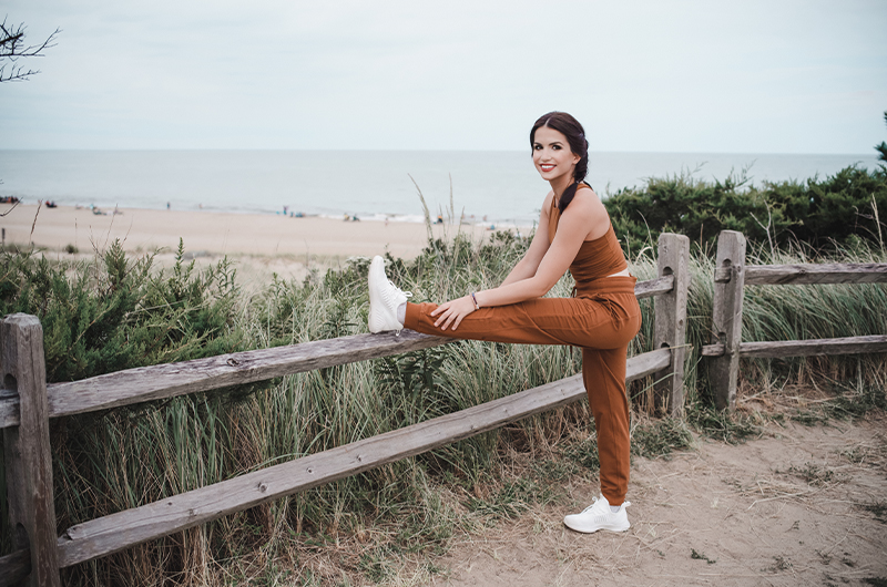 Six Self Care Strategies To Feel Your Bridal Best For Your Big Day Woman Stretching With Leg Up On Post On Beach Copy