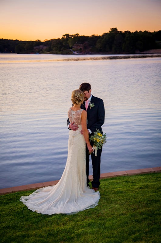 Lakepoint Restaurant And Event Center In Bella Vista Offers Breathtaking Backgrounds For Your Picturesque Dream Wedding Couple Kissing In Front Of Water Copy