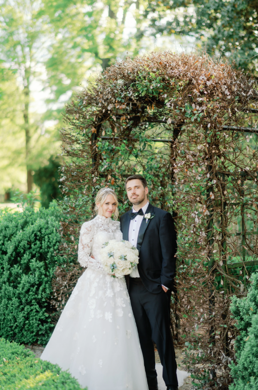 giselle palladino and jamie huzu real wedding couple in front of flower arch