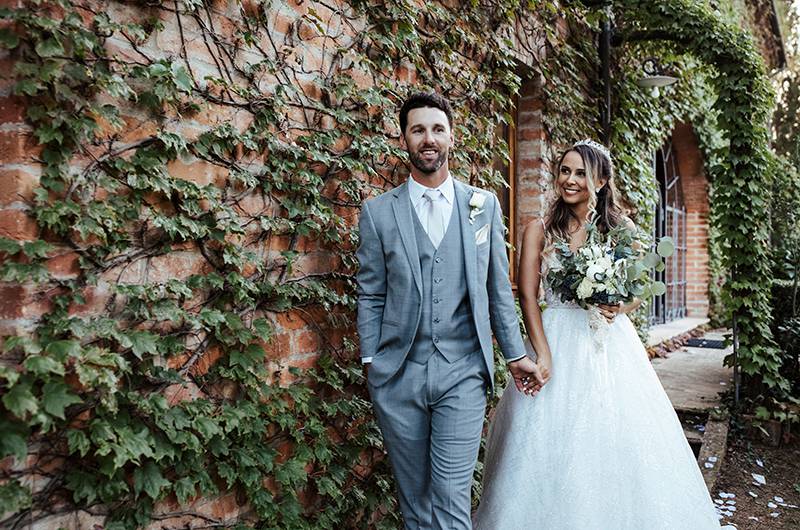 Stephanie MacLaughlin And Zachary Newell Couple In Front Of Vine Wall