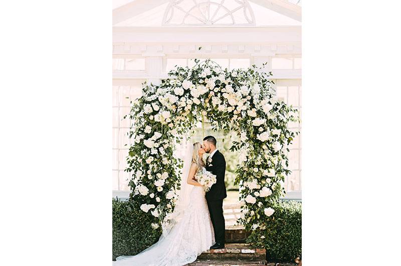 Bride and Groom At Heartwood Hall under white rose arch